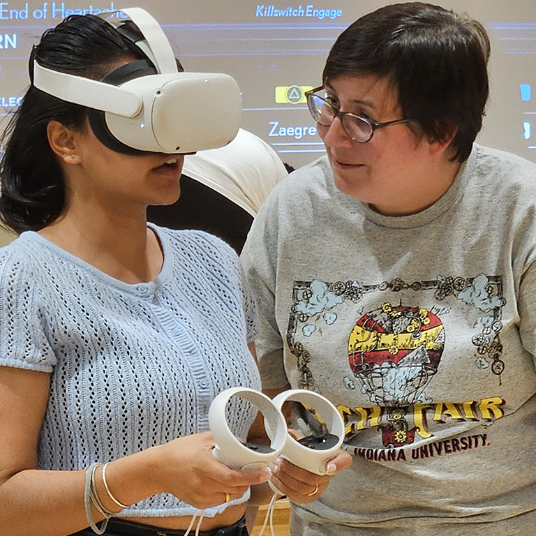 DEPI Student Outreach staffer Katie stands next to a student wearing a virtual reality headset at Tech Fair 2023.
